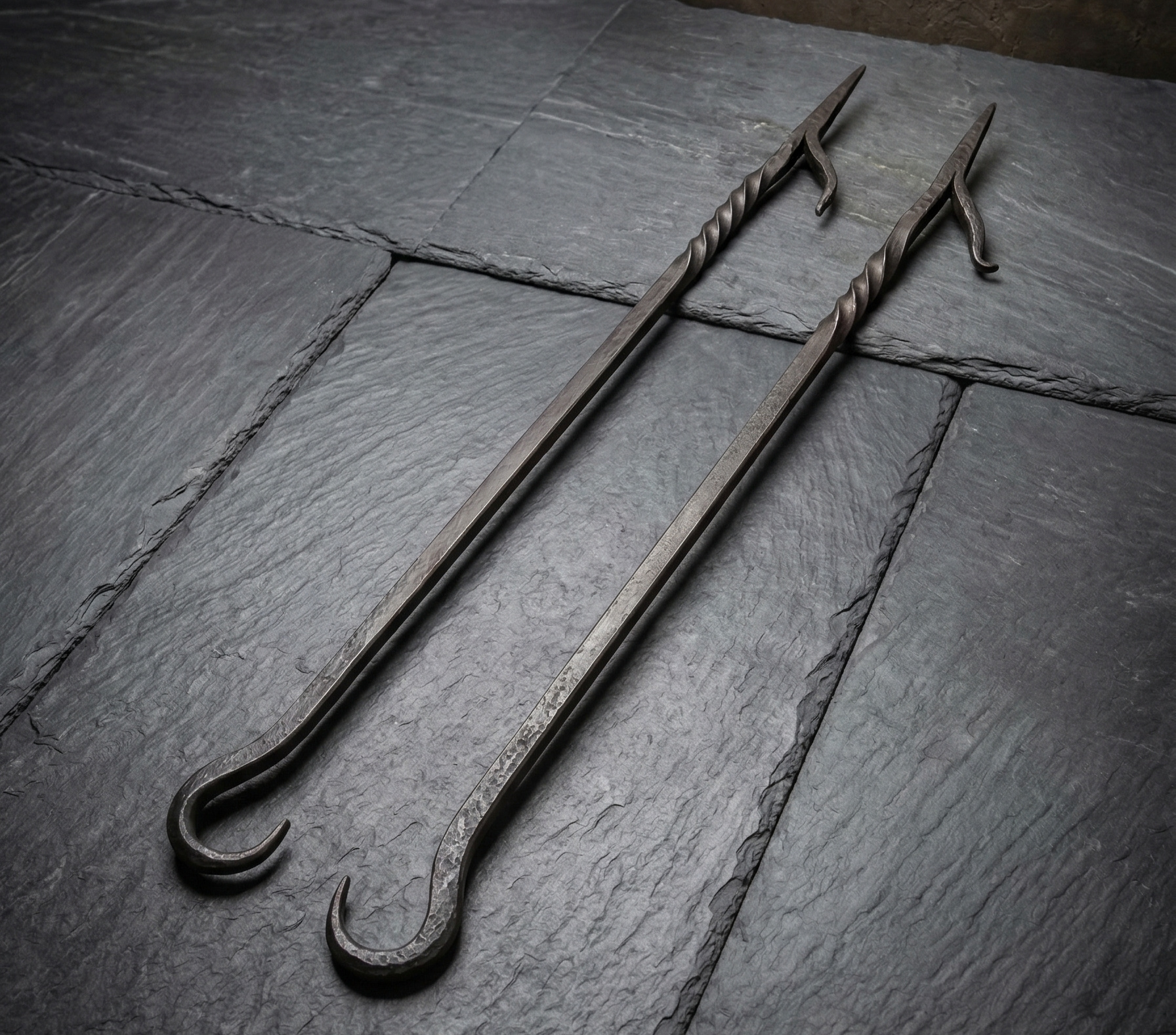 Pair of hand-forged twisted iron fire pokers on slate